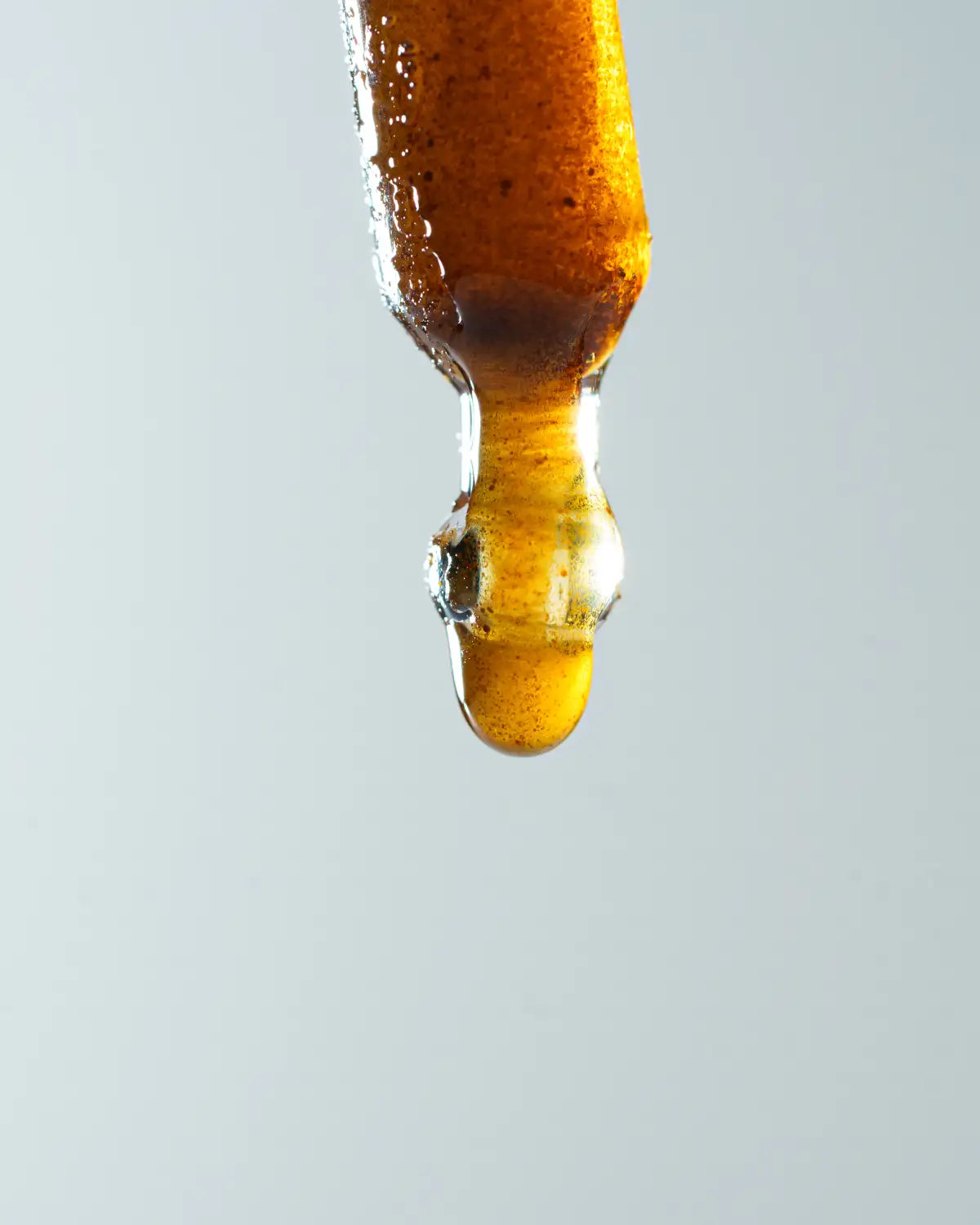 Nærbillede af en dråbe Aedel CBD-olie fra pipette – fremhæver den gyldne farve og fuldspektrede konsistens.