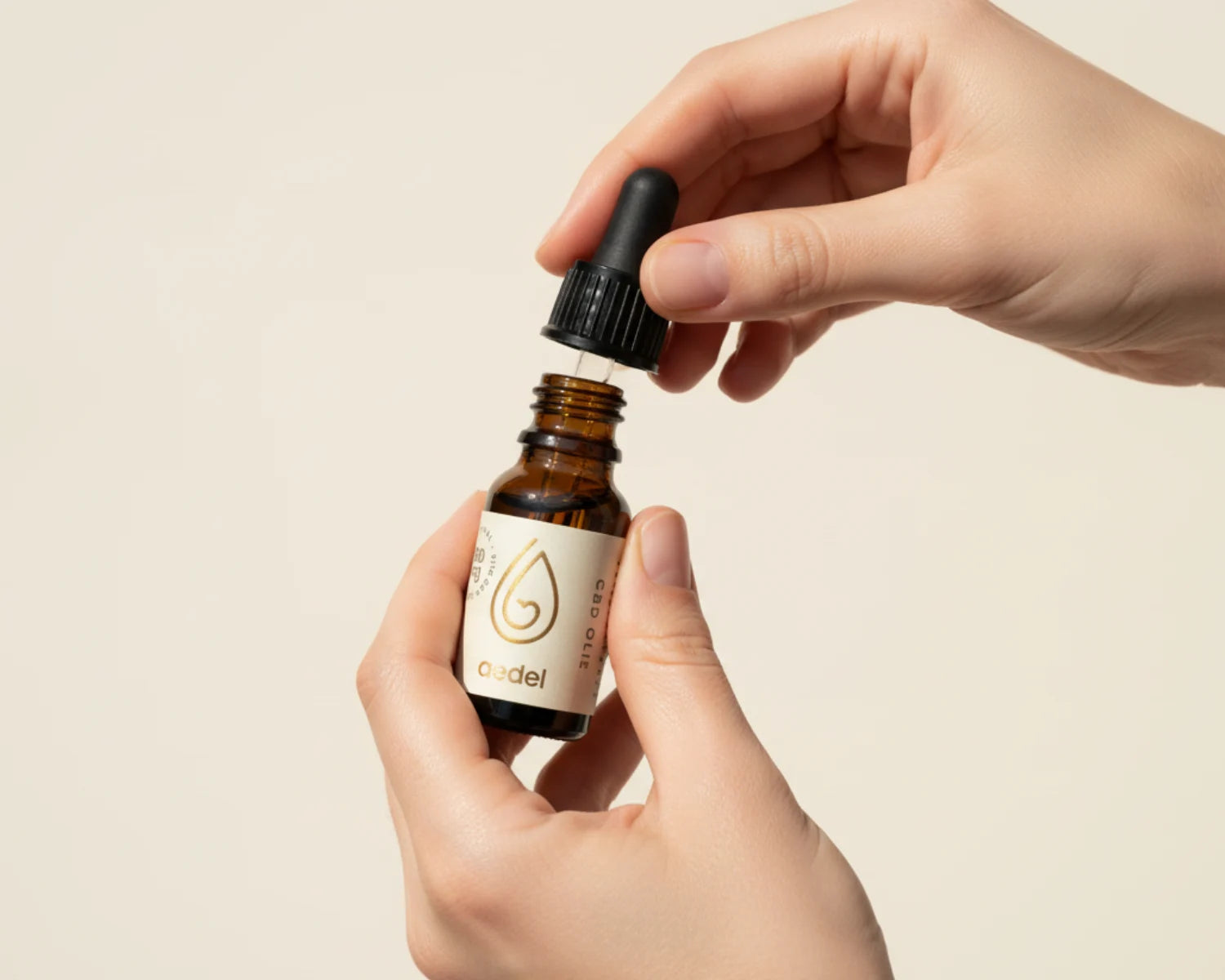 Hænder åbner en flaske Aedel CBD Olie med pipette – viser den naturlige, solventfri og fuldspektrede olie i elegant flaske.