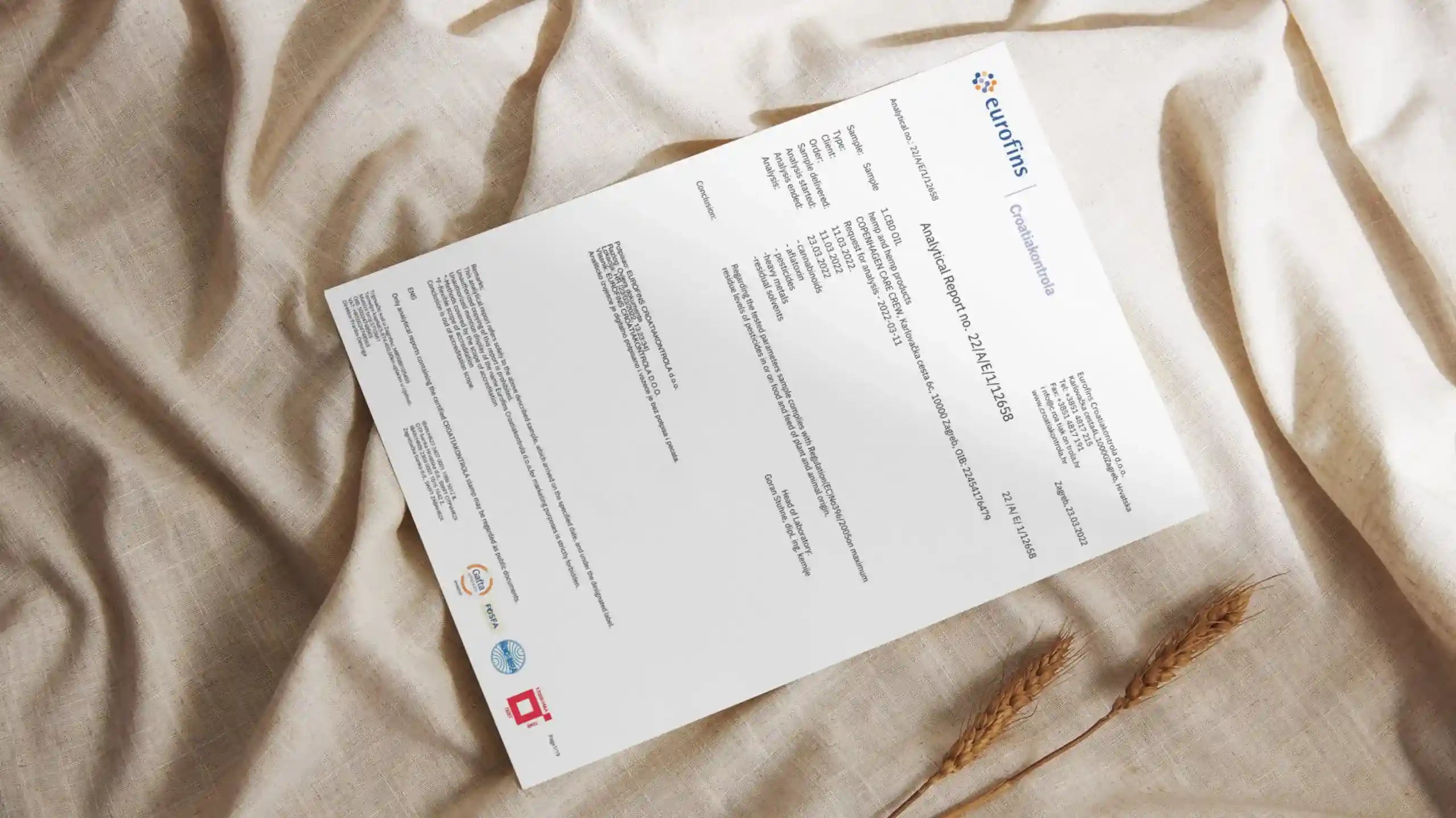 Foto af Eurofins laboratorierapport på lys stofbaggrund – viser Aedels gennemsigtighed og dokumenteret testning af hver batch.